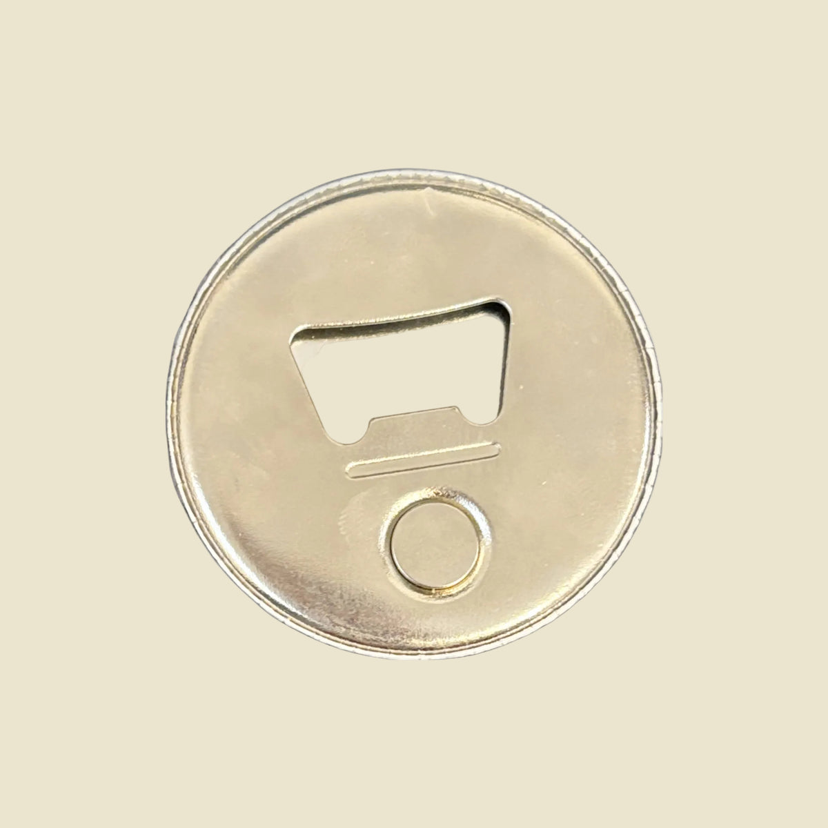 The back of a round metal bottle opener on a light yellow background.