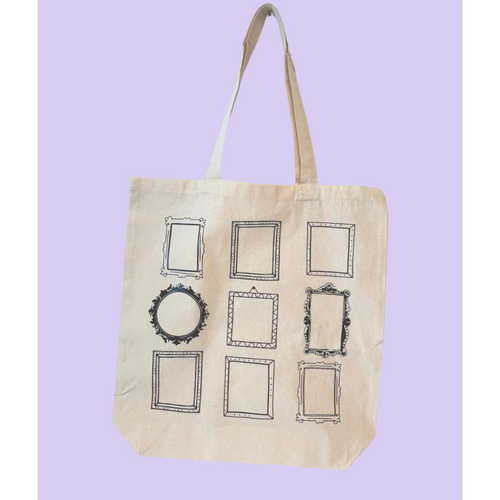 A natural canvas tote bag with nine black-framed picture frame prints on the front, set against a solid light purple background.